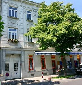 ein großes Gebäude mit einem Baum davor in der Unterkunft Suite Apartment Jedlesee in Wien