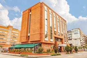 a large brick building with a green awning in front at Hotel Parque 97 Suites in Bogotá