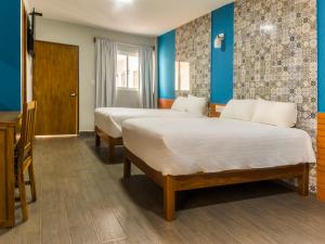 2 camas en una habitación con paredes azules en Hotel Meson del Barrio en Veracruz