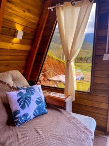 a bedroom with a bed with a window with a view at Morada do Corujão - Encanto in Praia Grande