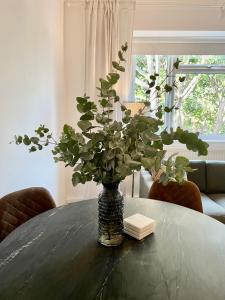 eine Vase voller grüner Pflanzen auf einem Tisch in der Unterkunft Newly refurbished 2 BR Apartment in South London in London