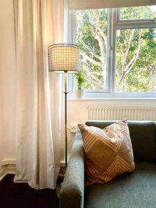 une lampe assise à côté d'un canapé devant une fenêtre dans l'établissement Newly refurbished 2 BR Apartment in South London, à Londres