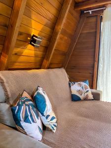 a couch with pillows on it in a room at Morada do Corujão - Aconchego in Praia Grande