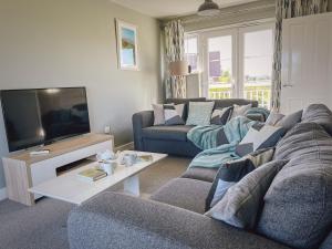 a living room with a couch and a tv at Marine House in Camber