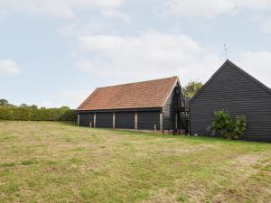 two barns with a grassy field in front of them at The Cart Lodge, Kettlebaston in Ipswich