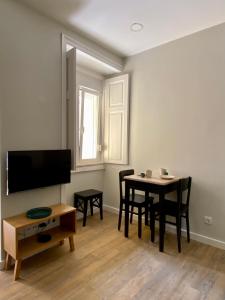 een woonkamer met een tafel en stoelen en een televisie bij Canarios Apartments Cardal - I in Lissabon