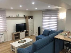 a living room with a blue couch and a tv at Piso céntrico León 2 in León