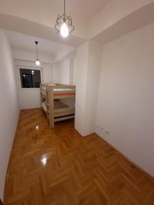 een lege kamer met een bed en een houten vloer bij Big apartment in Podgorica