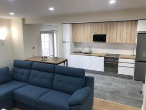 a living room with a blue couch and a kitchen at Piso céntrico León 2 in León