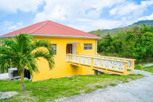 a yellow house with a balcony and a palm tree at Glasgow Villa at La Mar in Laborie