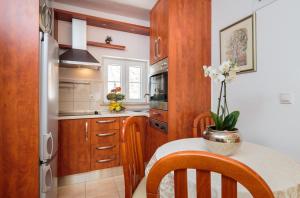 a kitchen with wooden cabinets and a table with a vase of flowers at Seaside house for families with children Sutivan, Brac - 20131 in Sutivan