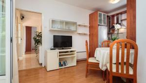 ein Wohnzimmer mit einem Tisch und einem TV im Zimmer in der Unterkunft Seaside house for families with children Sutivan, Brac - 20131 in Sutivan