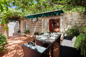 einen Tisch und Stühle in einem Hof mit einem Steingebäude in der Unterkunft Seaside house for families with children Sutivan, Brac - 20131 in Sutivan