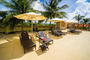 een patio met stoelen, tafels en parasols bij Paradiso Resort & Spa in Saipan