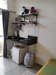 a kitchen with a stove and a shelf with pots and pans at Refúgio Ouro Fino Kitnets Casas e Apartamentos in Paraty
