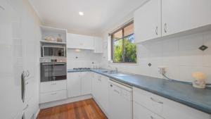 a white kitchen with white cabinets and a window at Tranquility At Lighthouse Beach in Port Macquarie