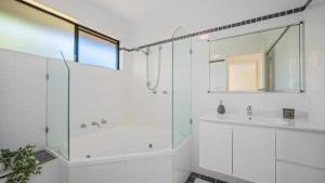 baño blanco con ducha y lavamanos en Tranquility At Lighthouse Beach en Port Macquarie