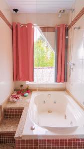 een groot bad in een badkamer met rode gordijnen bij Pousada Araucária Suítes in Campos do Jordão
