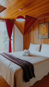 1 dormitorio con 1 cama grande y cortina roja en Pousada Araucária Suítes en Campos do Jordão