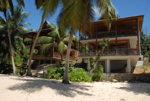 una casa en la playa con palmeras en LÌlot Beach Chalets, en Glacis