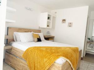 Un dormitorio con una cama de madera con una manta amarilla. en Great apartment D1, en Guatemala