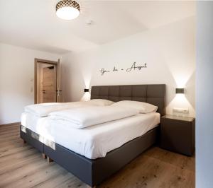 a bedroom with a large bed with white sheets at AUSZEIT Apartments in Oberau