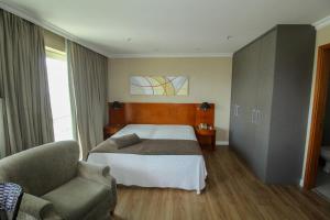 Habitación de hotel con cama y silla en Barra da Tijuca - Flat Premium com cozinha, completinho, moderno e muito confortável en Río de Janeiro