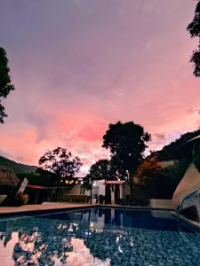 una piscina con puesta de sol en el fondo en Villa Cata Hotel, en El Zaino