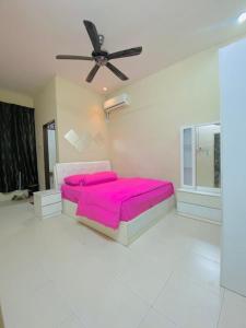 a bedroom with a pink bed and a ceiling fan at Homestay lagenda padang serai in Padang Serai