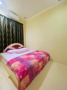 1 dormitorio con 1 cama con una manta colorida en Homestay lagenda padang serai en Padang Serai