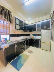 uma cozinha com armários a preto e branco e um frigorífico em Homestay lagenda padang serai em Padang Serai