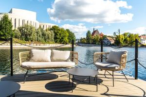 2 chaises et une table sur une terrasse à côté de l'eau dans l'établissement Dom Na Wodzie La Mare Houseboat, à Bydgoszcz