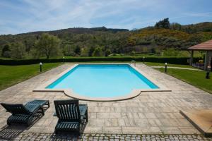 a swimming pool with two chairs and a table at Casa Da Eira Longa in Vilar