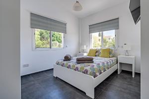 een witte slaapkamer met een bed en 2 ramen bij Villa Prasino in Coral Bay