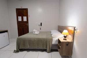 a small bedroom with a bed and a night stand at Hotel Verde Mares in Macapá