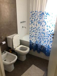 a bathroom with a white toilet and a blue shower curtain at Palermo Tessa I Appartment in Buenos Aires