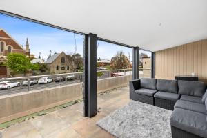 a living room with a couch and large windows at The SCOOP in Queenscliff