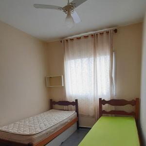 1 Schlafzimmer mit 2 Betten und einem Fenster mit einem Deckenventilator in der Unterkunft Apartamento super arejado na Praia do Morro in Guarapari