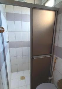 baño con ducha, aseo y puerta en Apartamento super arejado na Praia do Morro, en Guarapari