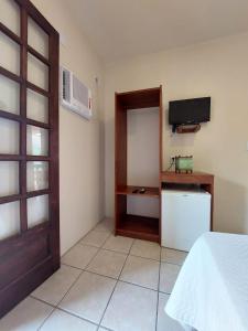 Zimmer mit einem Bett, einem TV und einer Tür in der Unterkunft Pousada Don Antonio Praia - 50 metros da Praia! in Garopaba
