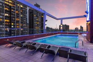 a large swimming pool with chairs and tables in front of a building at Ramada Hong Kong Harbour View in Hong Kong