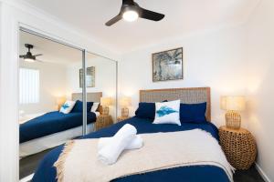 a bedroom with two beds and a mirror at Spinnaker 201 in Forster