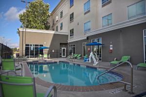 una piscina con sillas verdes y un edificio en Holiday Inn Hotel & Suites Northwest San Antonio, an IHG Hotel en San Antonio