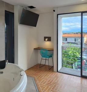 uma casa de banho com uma banheira, uma janela e uma cadeira em Hotel Macaw Cúcuta em Cúcuta