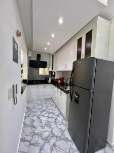 a kitchen with a refrigerator and a marble floor at Acogedor apartamento 2 hab Distrito nacional, próximo agora mall in Santo Domingo