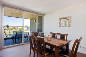 Un comedor con mesa y sillas y un balcón. en Resort Penthouse 301, en Torquay