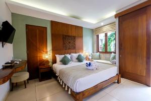 a bedroom with a bed and a desk and a bed sidx sidx sidx at Kakul Villas & Suites in Ubud