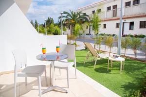 a patio with a table and chairs and grass at Loutsiana Deluxe Apts in Ayia Napa