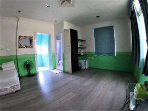 an empty living room with green walls and wooden floors at Islander B&B in Xiaoliuqiu