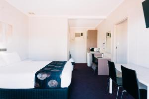a hotel room with a bed and a table and chairs at Motel Poinsettia in Port Augusta